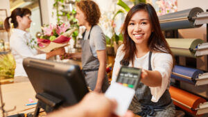 Retail Woman Giving Machine To Pay 300x169